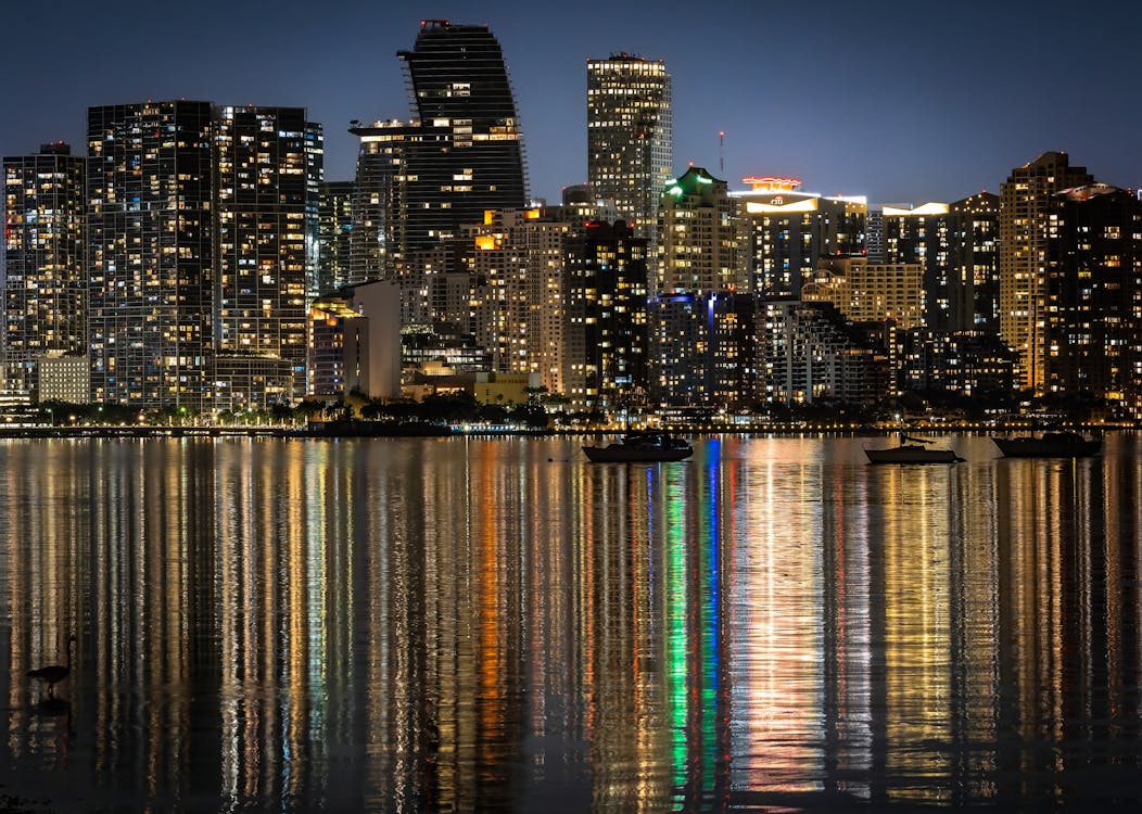 Downtown Miami skyline lit up at night reflected across Biscayne Bay, illustrating the metro's deep year-round million-dollar condo inventory