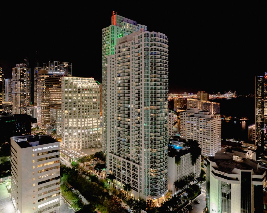 Brickell condo tower lit up at night above the Miami skyline in Florida