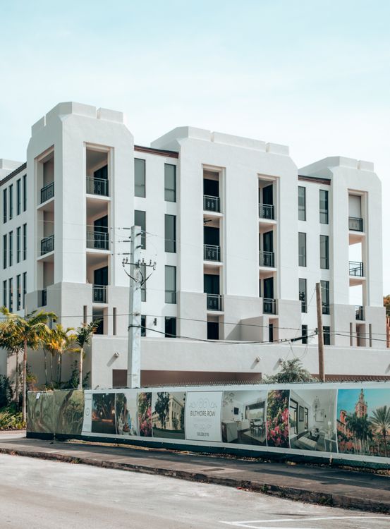 Miami luxury condo with construction hoarding and a sales banner, the stalled-launch scenario buyers should read as negotiating leverage