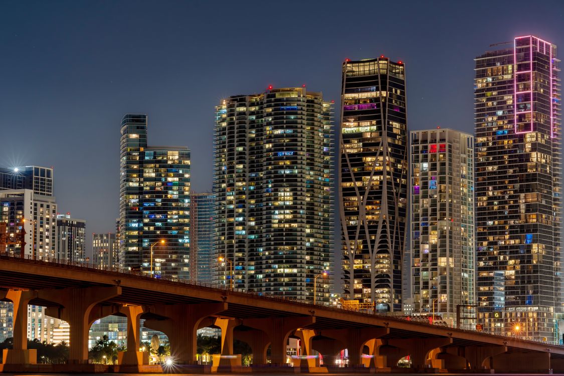 Miami luxury condo towers lit up at night near the waterfront, the Brickell and Edgewater units commanding premium World Cup 2026 rental rates