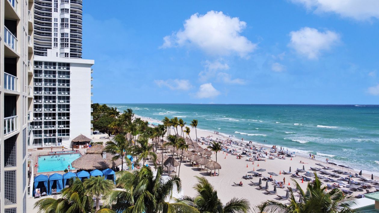 An oceanfront Miami condo tower above a wide sandy beach, the kind of branded pre-construction inventory foreign buyers acquire on a multi-year deposit schedule