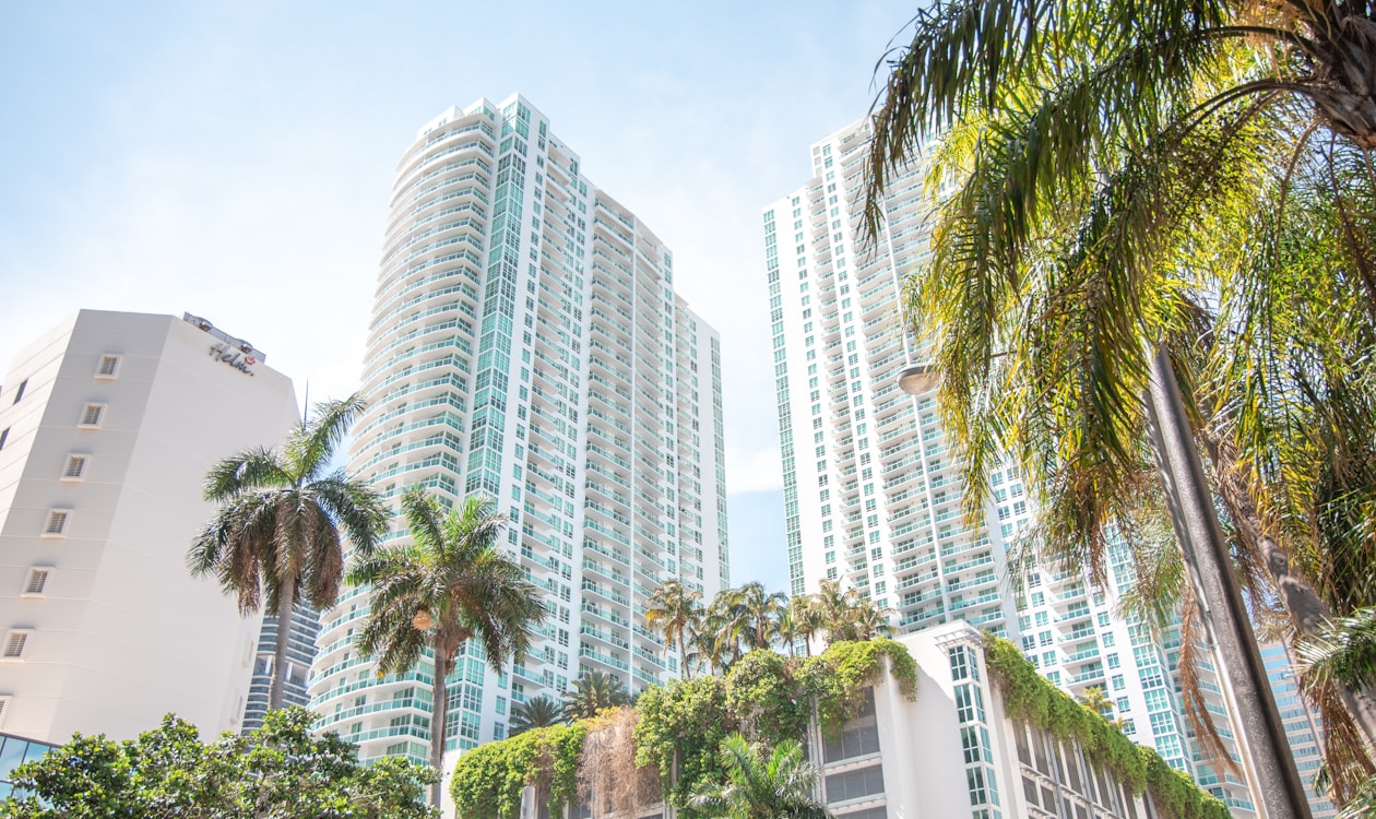 Twin glass Miami luxury condo towers framed by palm trees, the branded-residences product type that trades at a premium worldwide