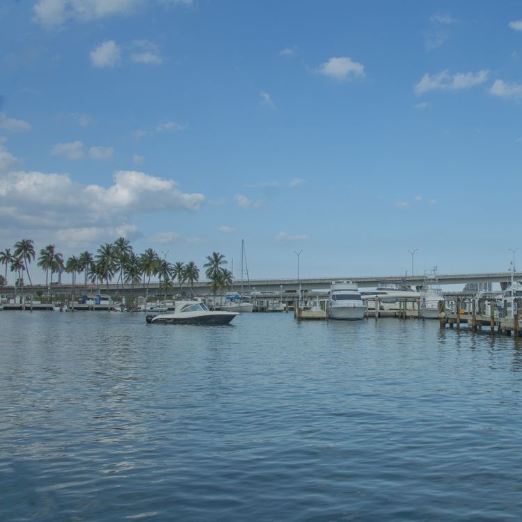 Boats docked at a Biscayne Bay marina beside a causeway, illustrating the on-water boating access planned at the North Bay Village project