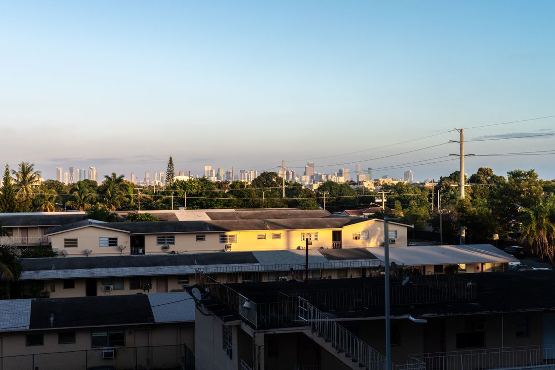 Older low-rise Miami apartments in the foreground with the downtown skyline rising behind, the density shift the Live Local Act accelerates across neighborhoods