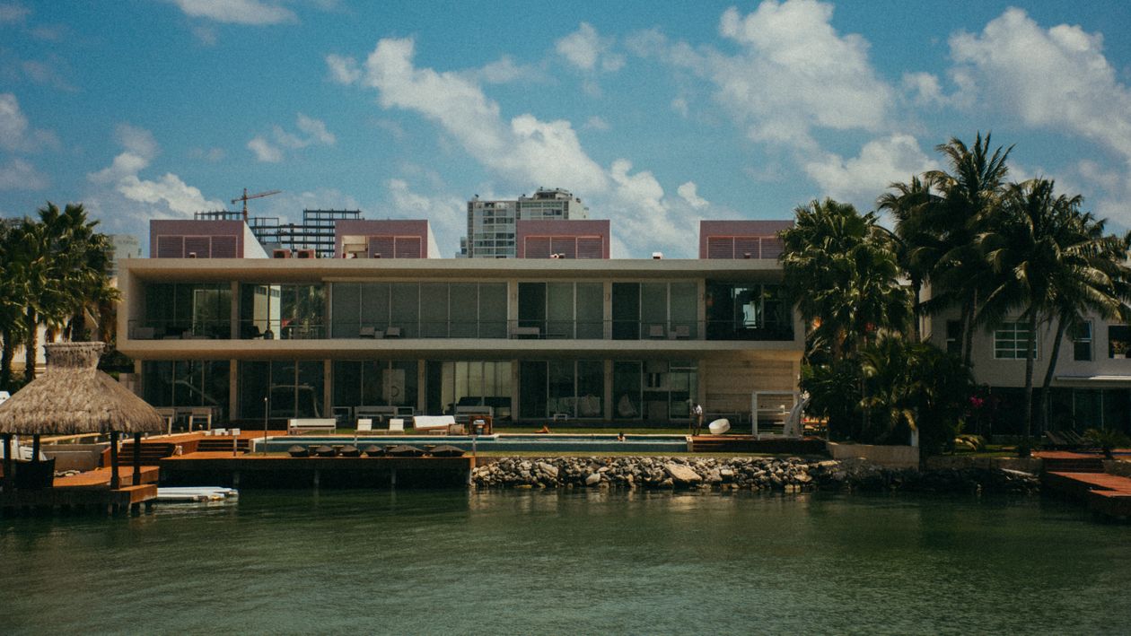 Modern new-construction waterfront home with a pool and Miami skyline behind it