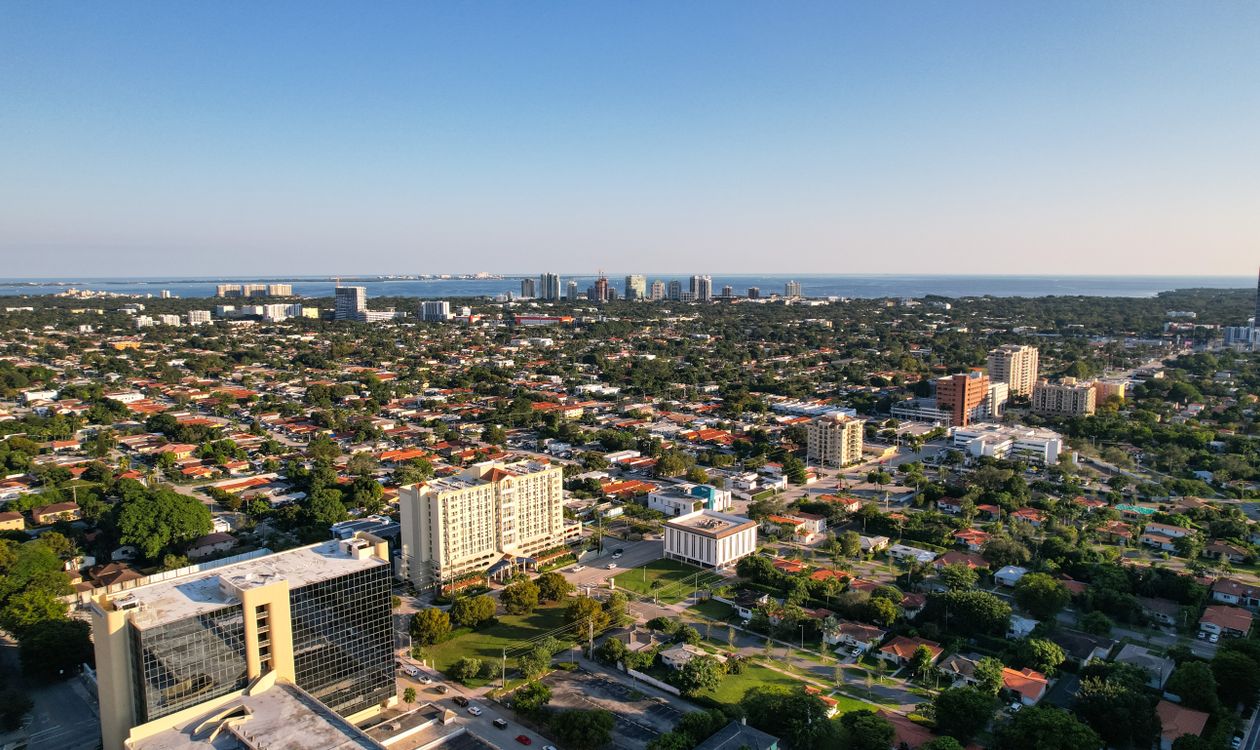 Aerial view over Miami neighborhoods looking toward the towers and open water of Biscayne Bay
