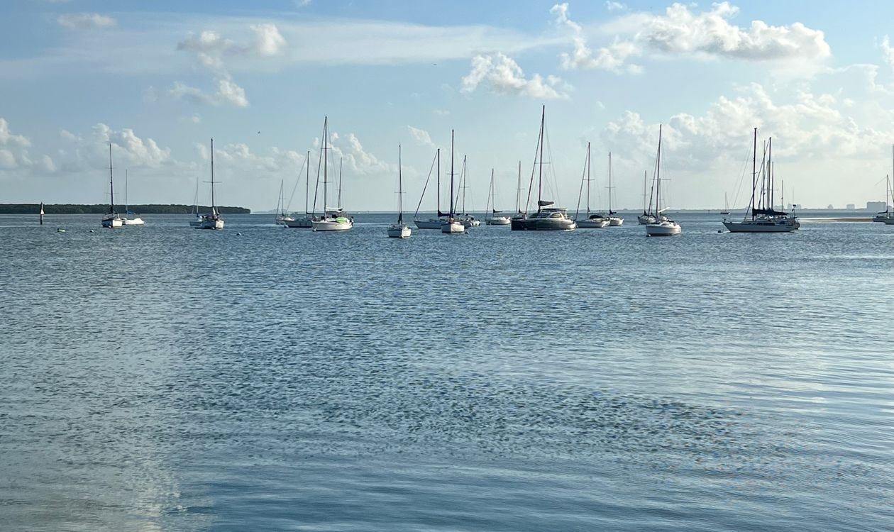 Sailboats anchored on calm Biscayne Bay water off Key Biscayne under a blue sky