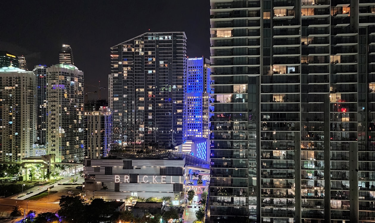 Illuminated Brickell condominium towers at night where Miami buyers are combining units into custom sky duplexes