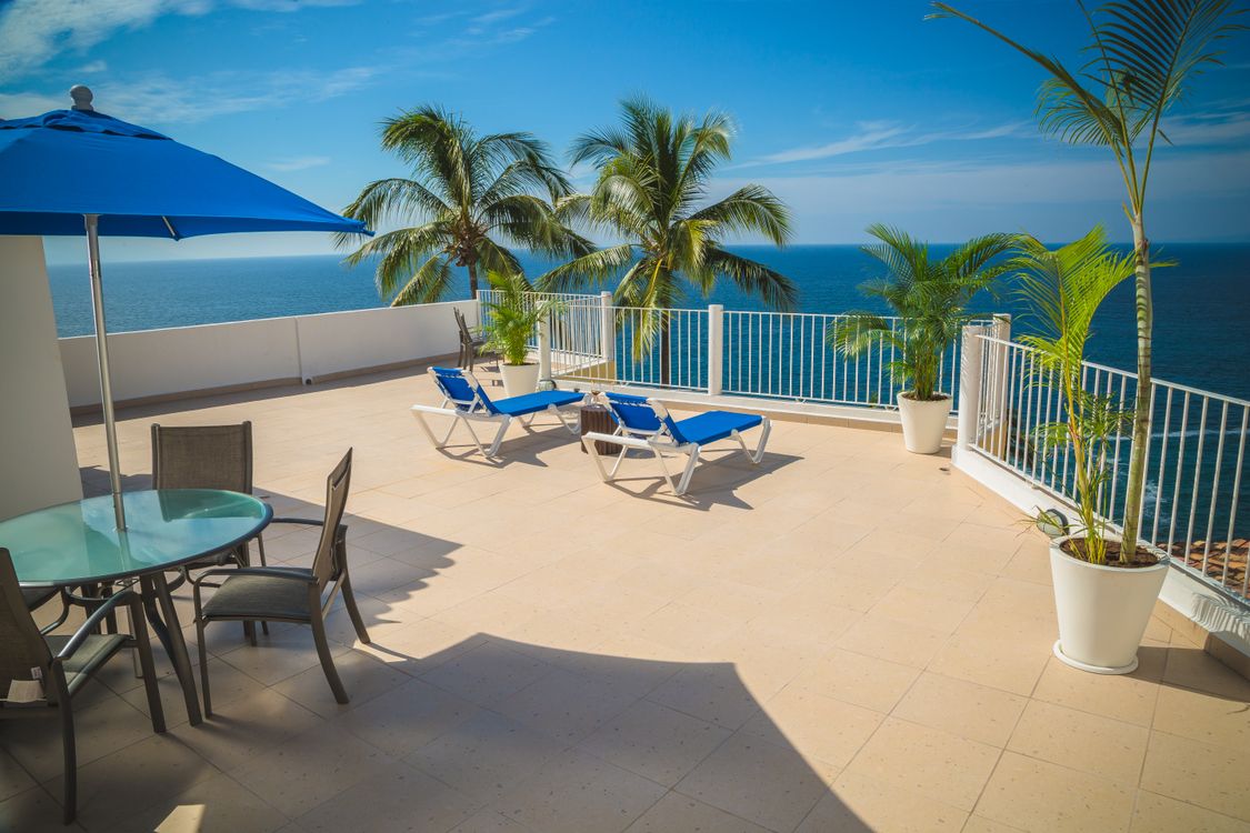 Expansive private oceanfront terrace with lounge chairs and palms on a Miami luxury residence