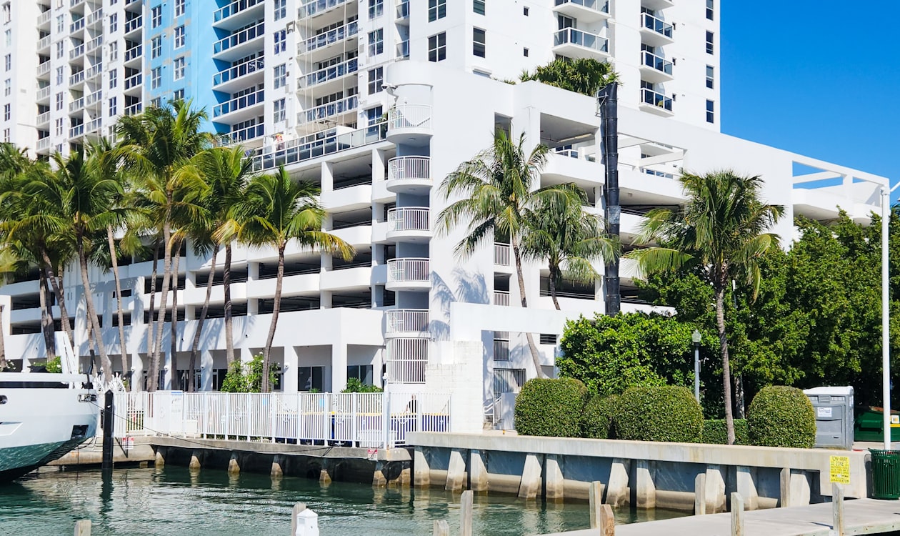 Waterfront Miami condominium building with palm trees and a moored yacht, the kind of tower where units are combined into larger homes