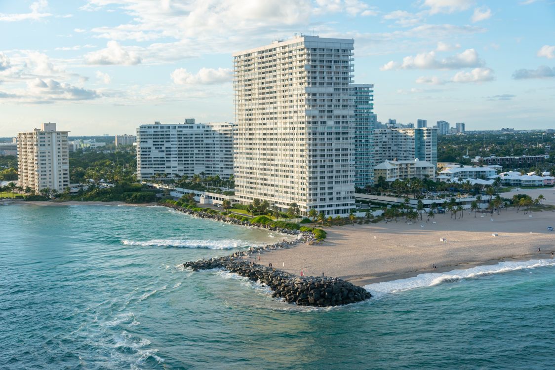 Aerial of oceanfront luxury condo high-rises on a South Florida beach with turquoise Atlantic water