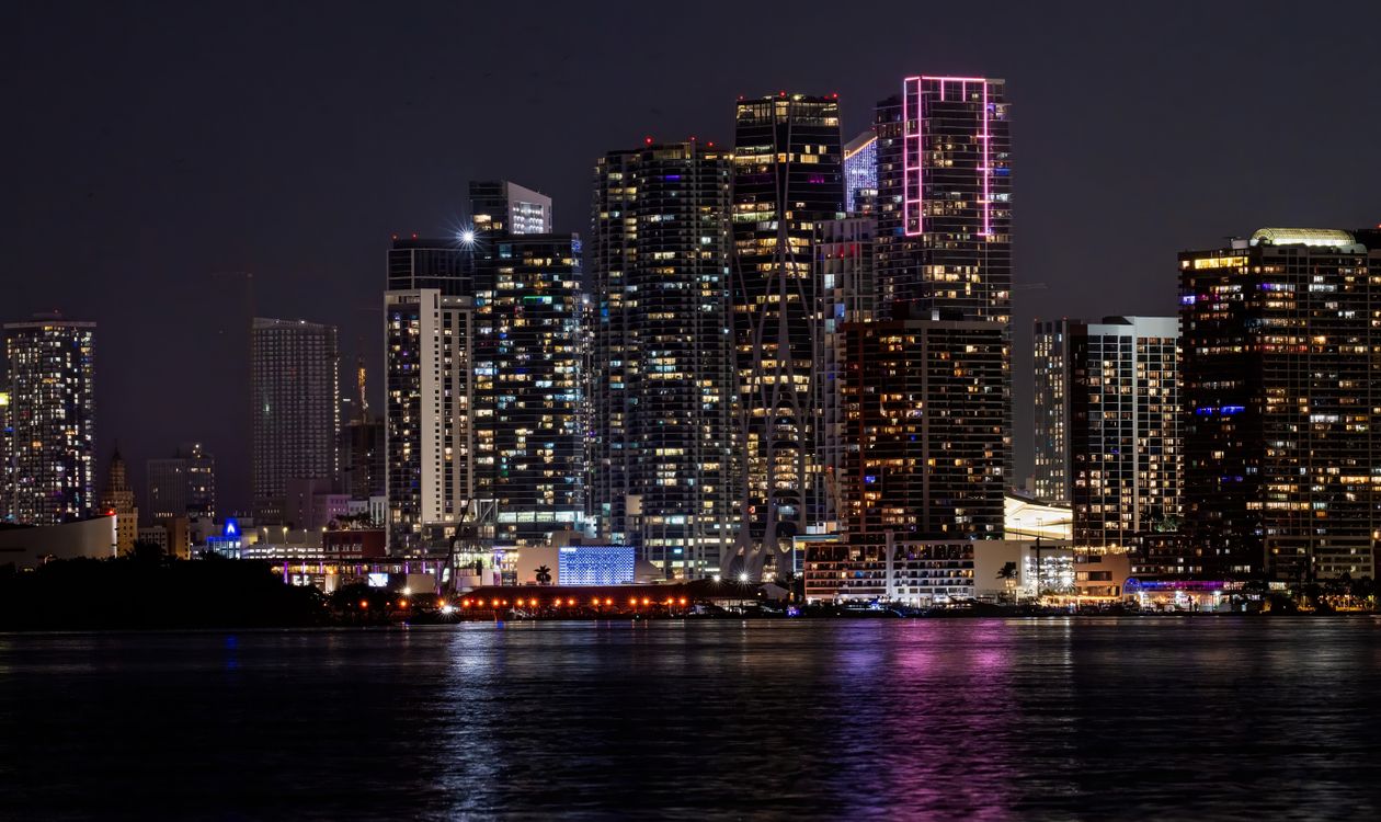 Illuminated Miami bayfront condominium skyline at night seen across Biscayne Bay