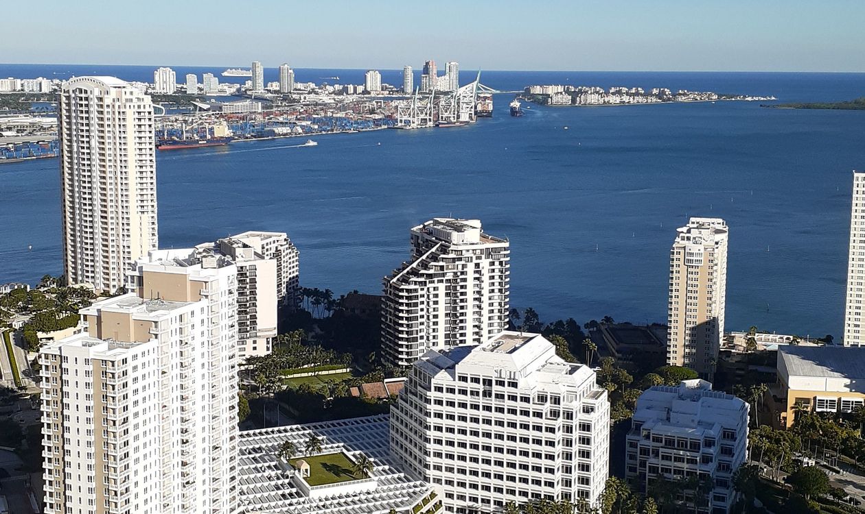 Brickell waterfront condo towers across Biscayne Bay with PortMiami and Fisher Island in the distance