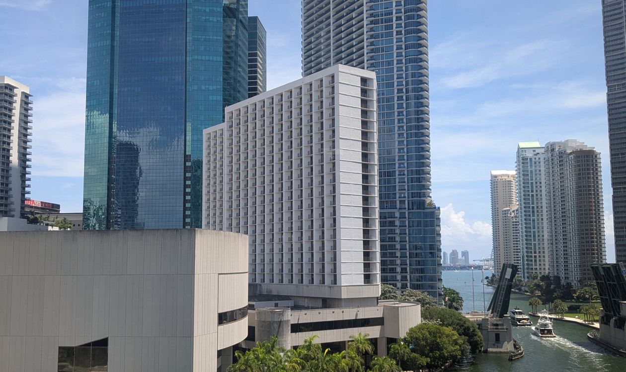 Brickell condominium tower on the Miami River surrounded by taller glass high-rises