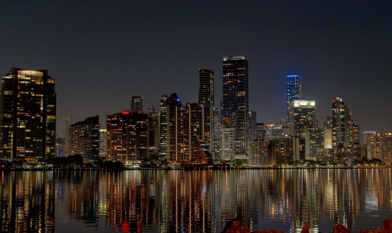 Brickell condominium and office towers lit at night reflected across Biscayne Bay in Miami