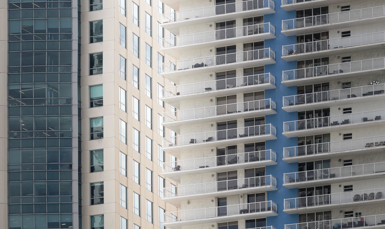Close view of individual condominium balconies stacked across a Miami high-rise facade, representing the separate units a bulk buyer must acquire one at a time