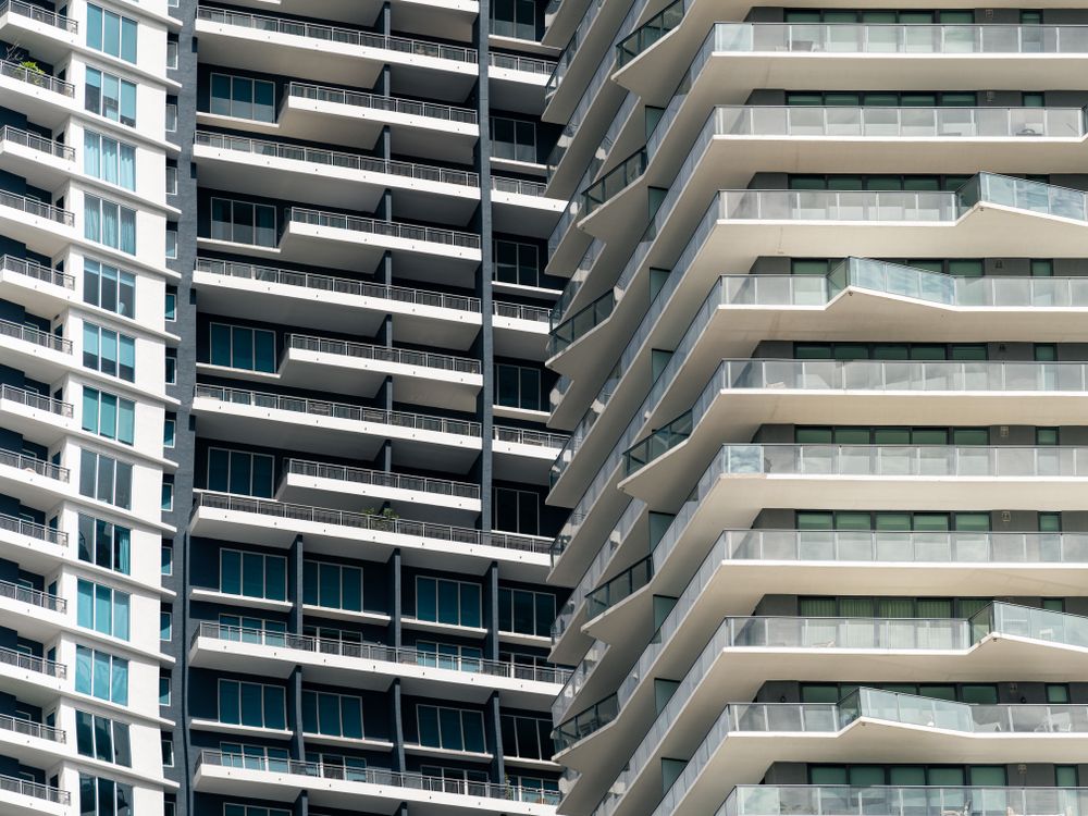 Diagonal view of stacked balconies on adjacent Miami residential high-rise towers with palm plantings on a terrace