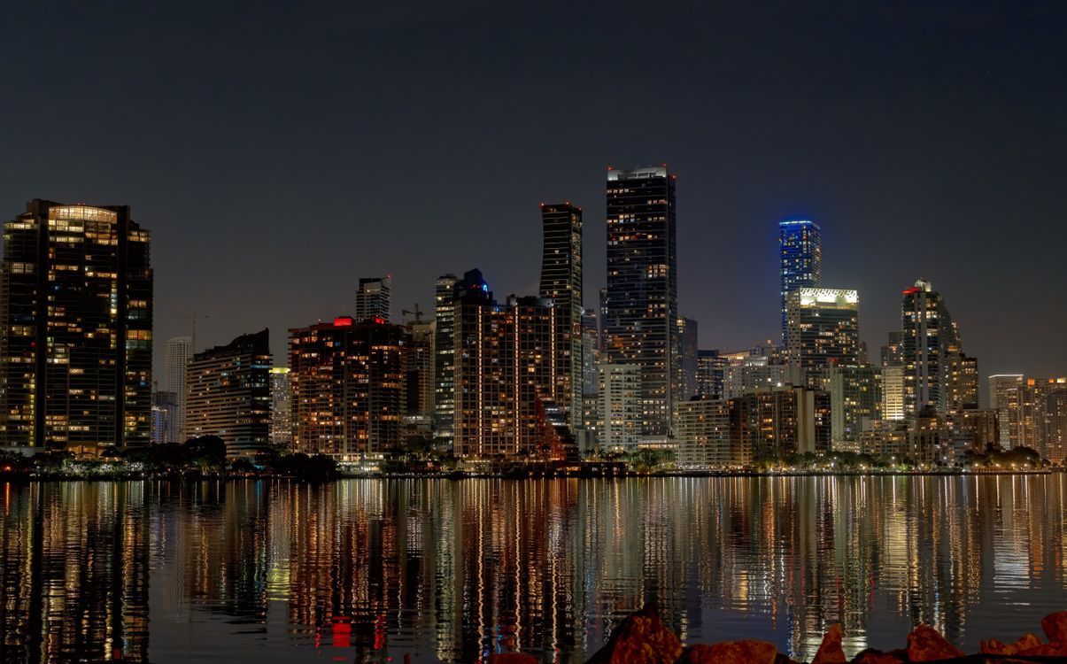 Brickell skyline of lit condo towers reflected across the water at night in Miami Florida