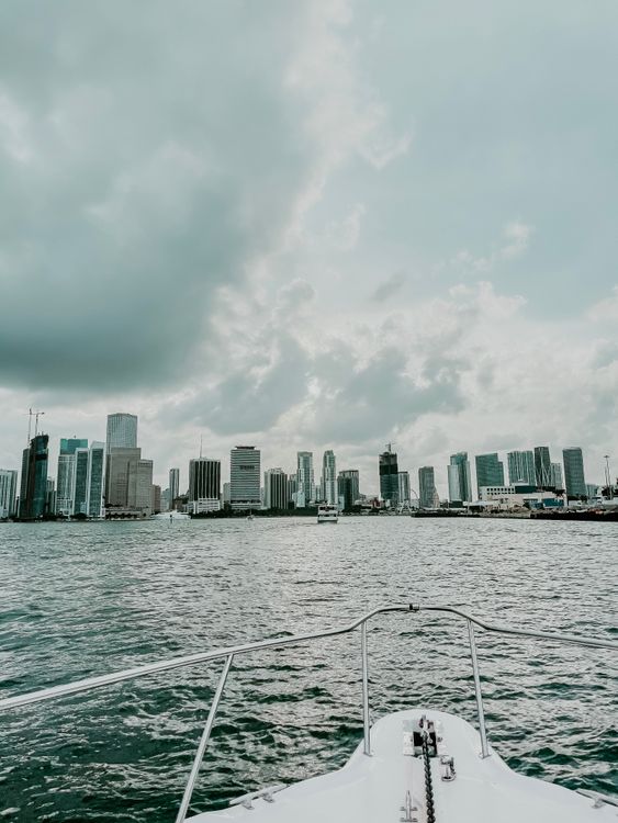 The downtown Miami skyline seen from Biscayne Bay under heavy cloud, with construction cranes visible along the waterfront
