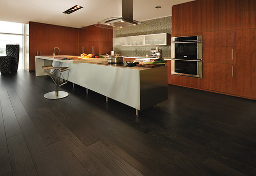 Interior of a modern Miami luxury condominium with a large island kitchen, floor-to-ceiling glass, and dark wood floors