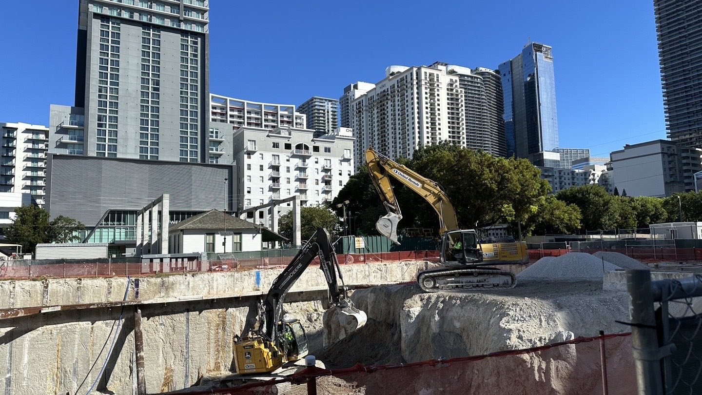 Excavation and foundation work at the 1 Southside Park construction site in Brickell, with Miami residential towers behind