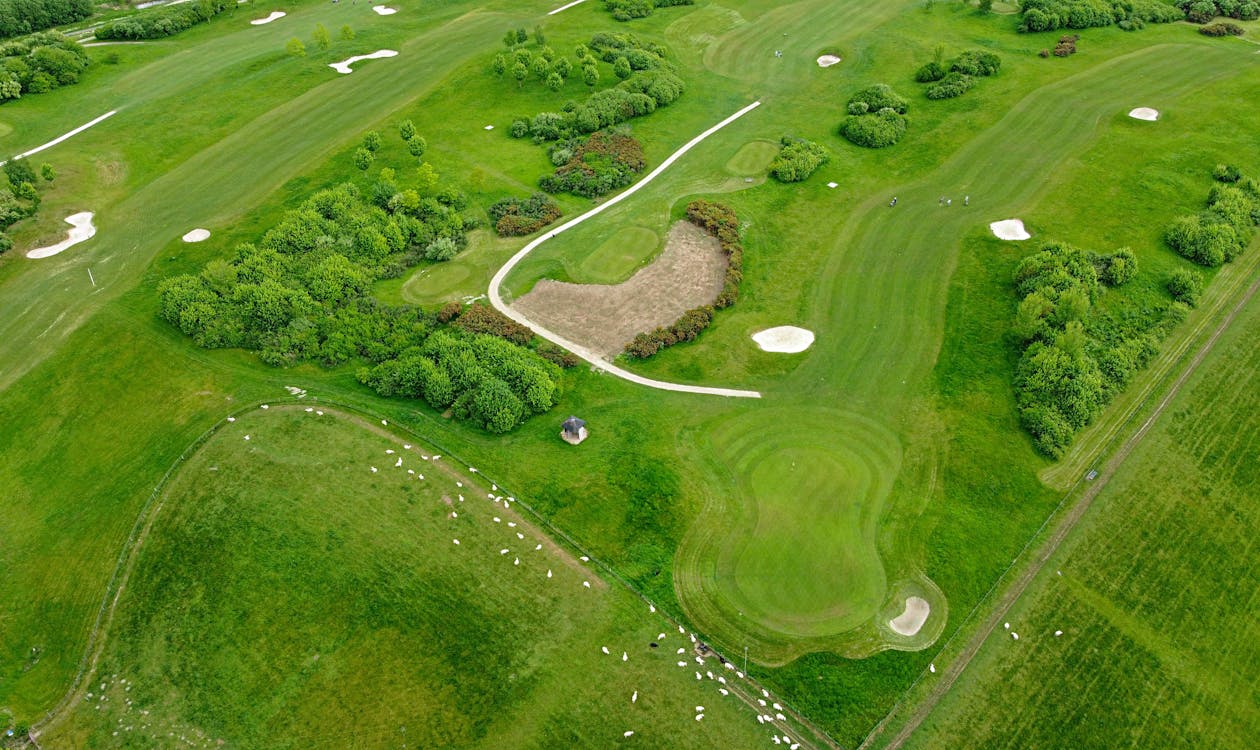 Aerial view of a Mediterranean Revival luxury tower with golf course fairways and tropical palms, representative of Trump National Doral and Doral's gated golf-estate communities