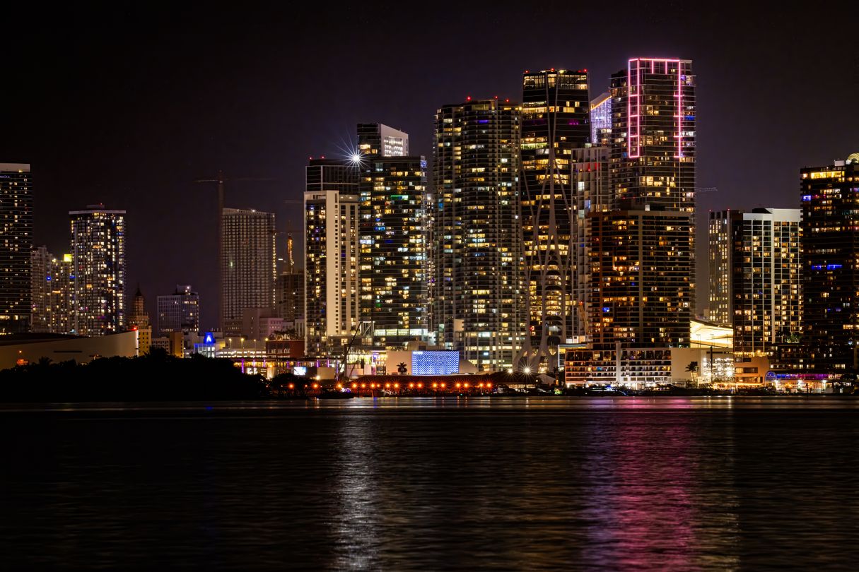 The downtown Miami skyline lit at night seen across the water of Biscayne Bay