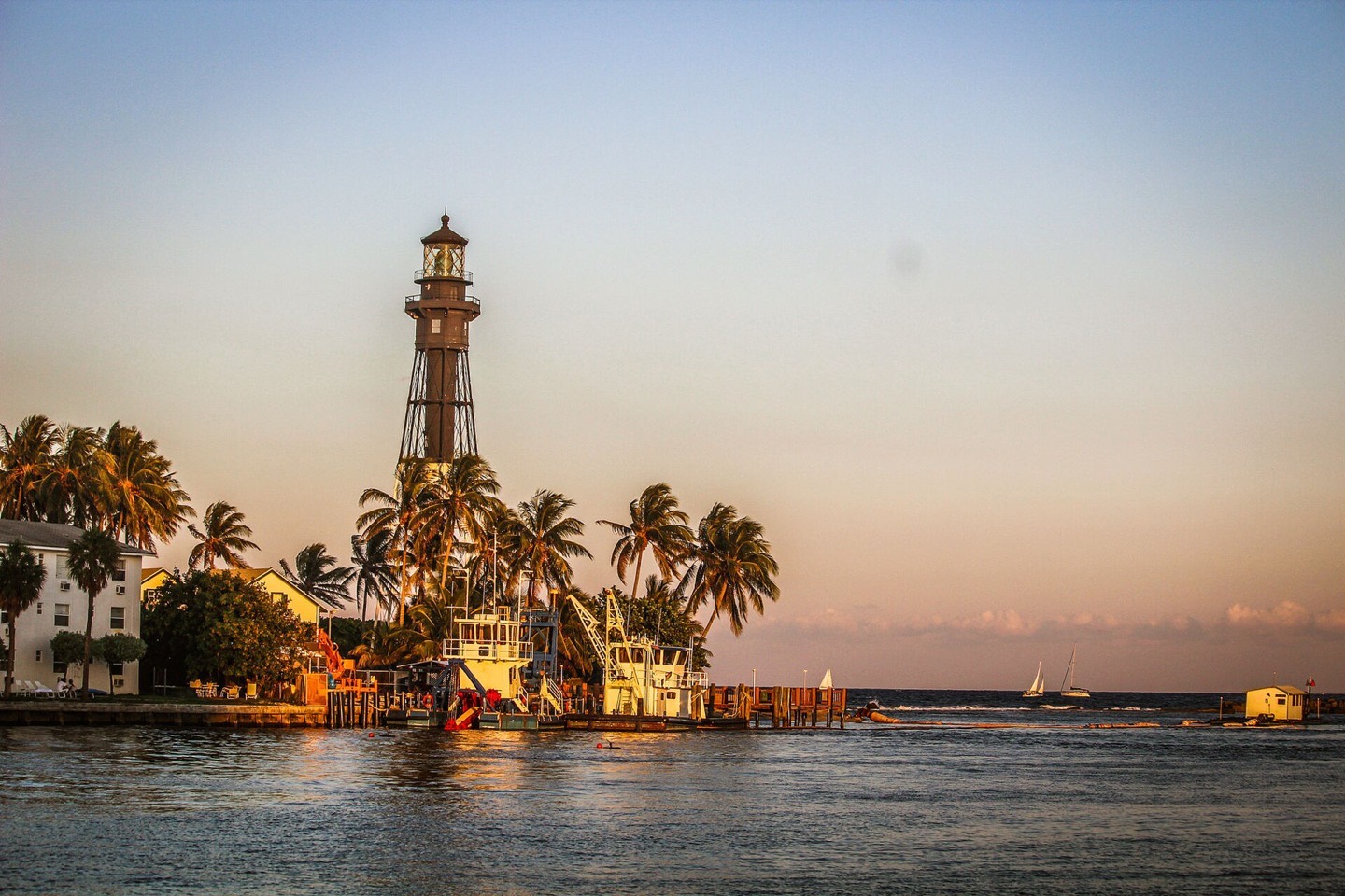 Hillsboro Inlet Lighthouse at sunset with boats on the inlet channel in Hillsboro Beach, Florida