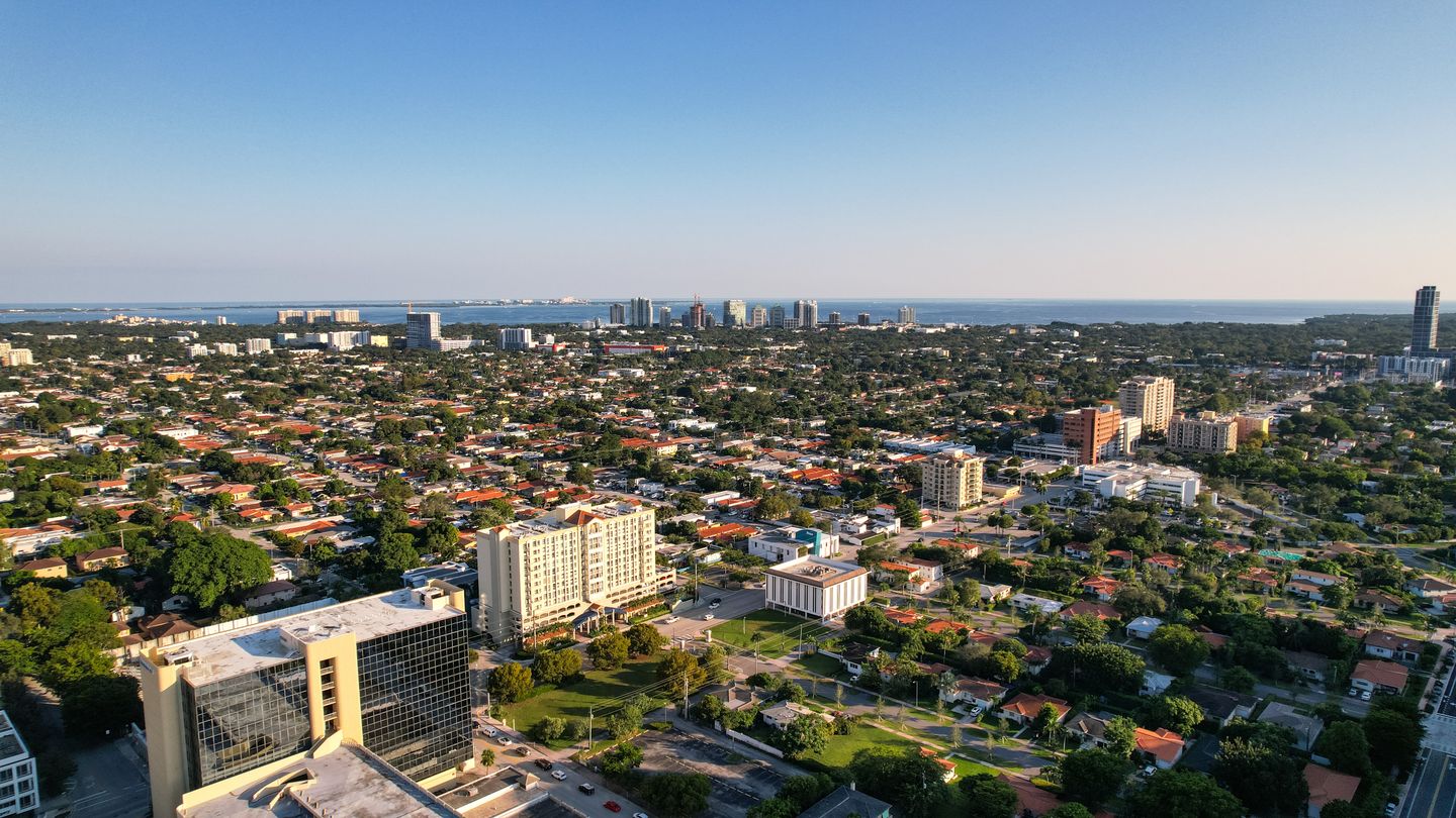 Aerial view of Miami single-family blocks with condo towers along the Biscayne Bay horizon