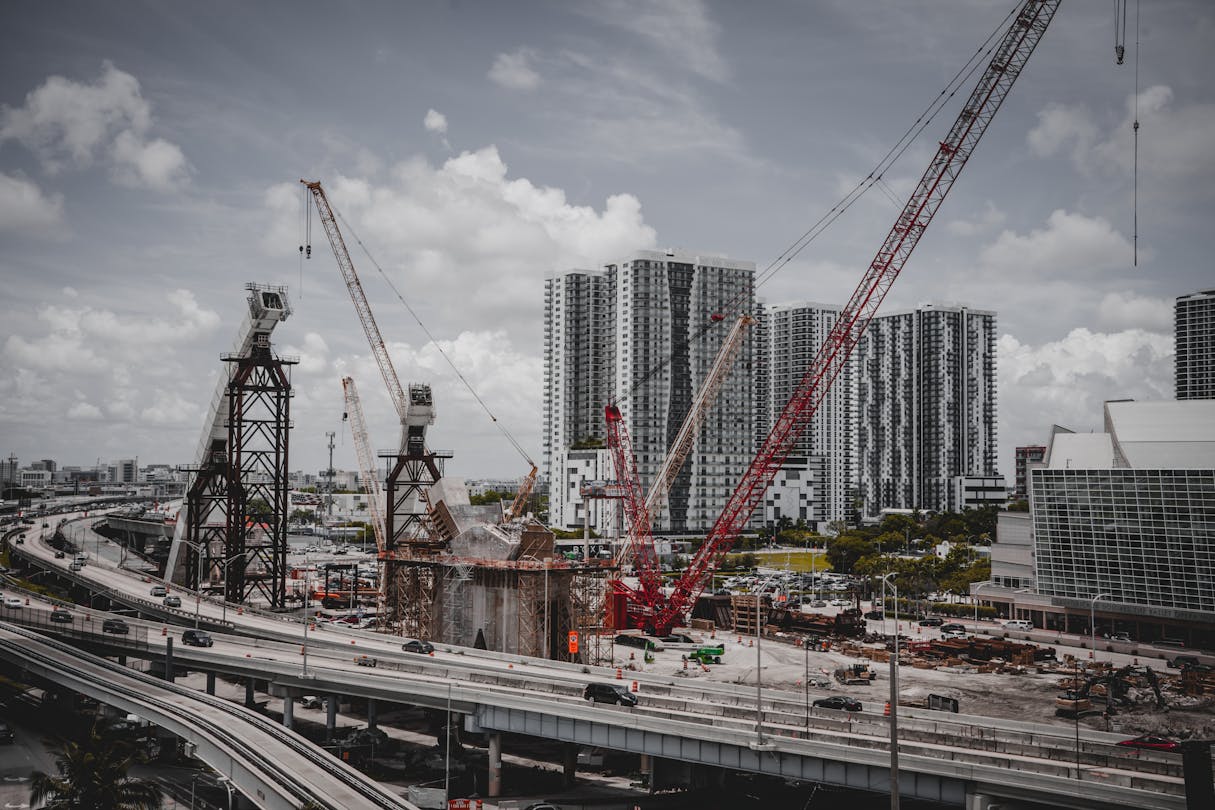 Tower crane rising over a Miami condo under construction against a clear sky