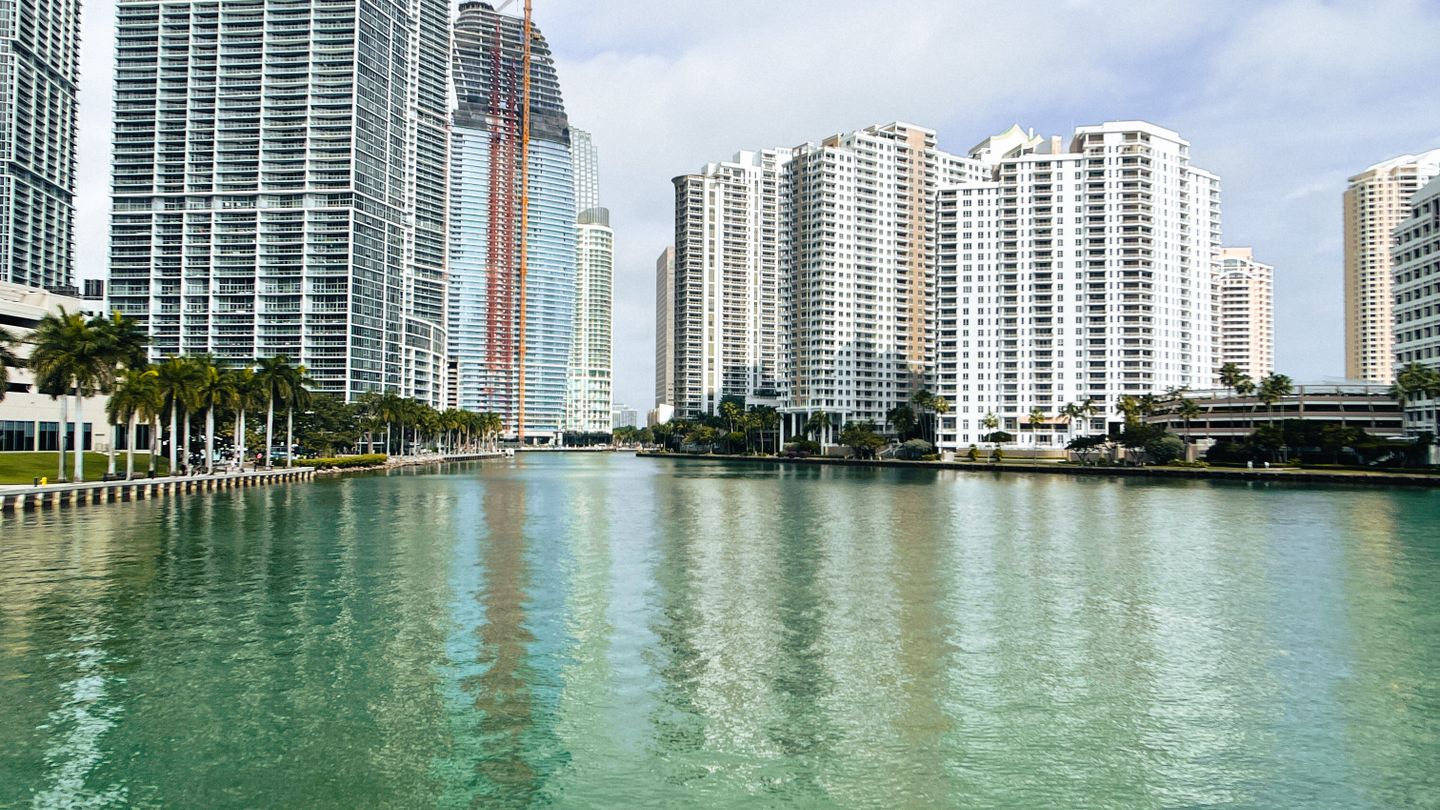 Brickell luxury condo towers reflecting on the water, where foreign buyers absorb nearly half of new construction
