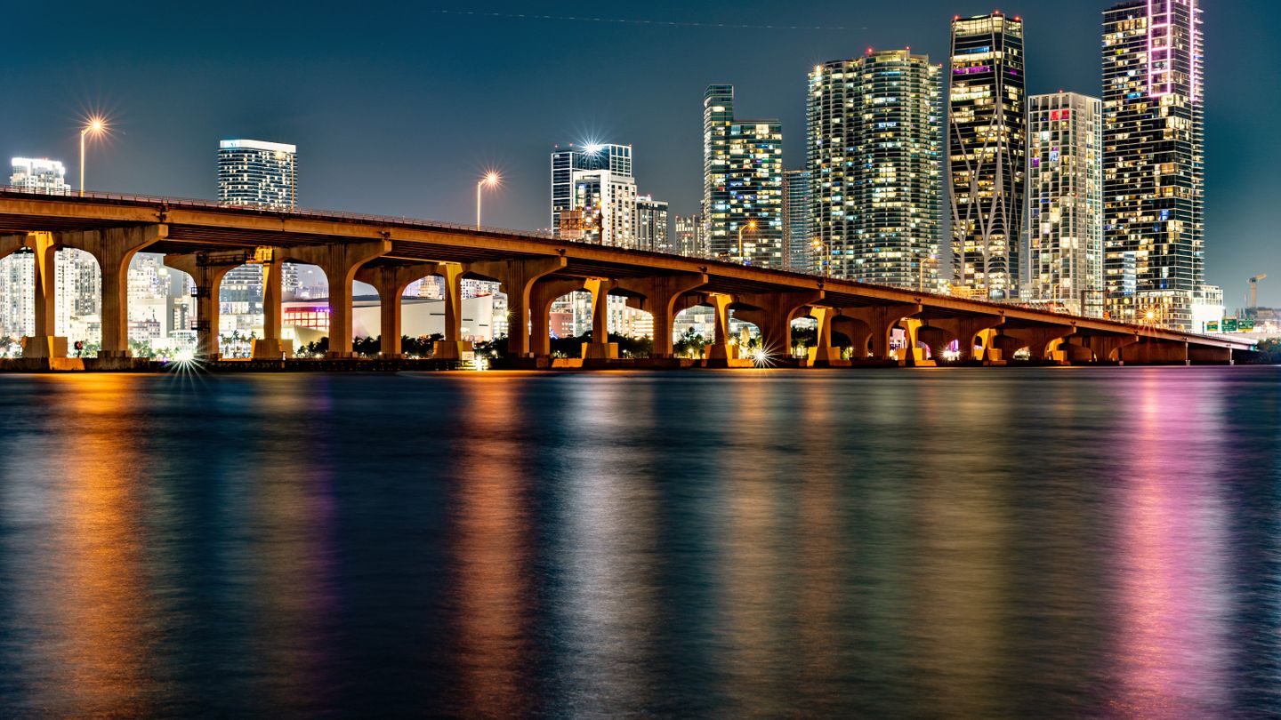 Illuminated Venetian Causeway over Biscayne Bay with the downtown Miami condo skyline at night in 2026