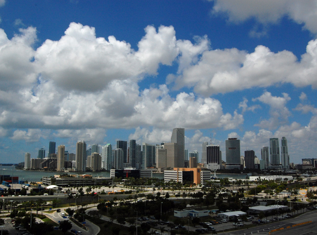 Downtown Miami skyline seen across Biscayne Bay under a bright cloudy sky
